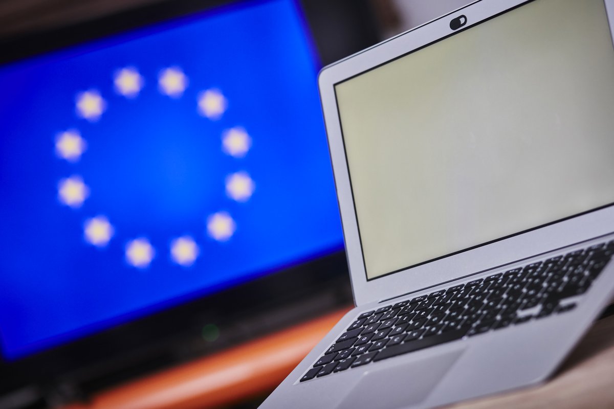 A computer with a white screen and the European flag in the background