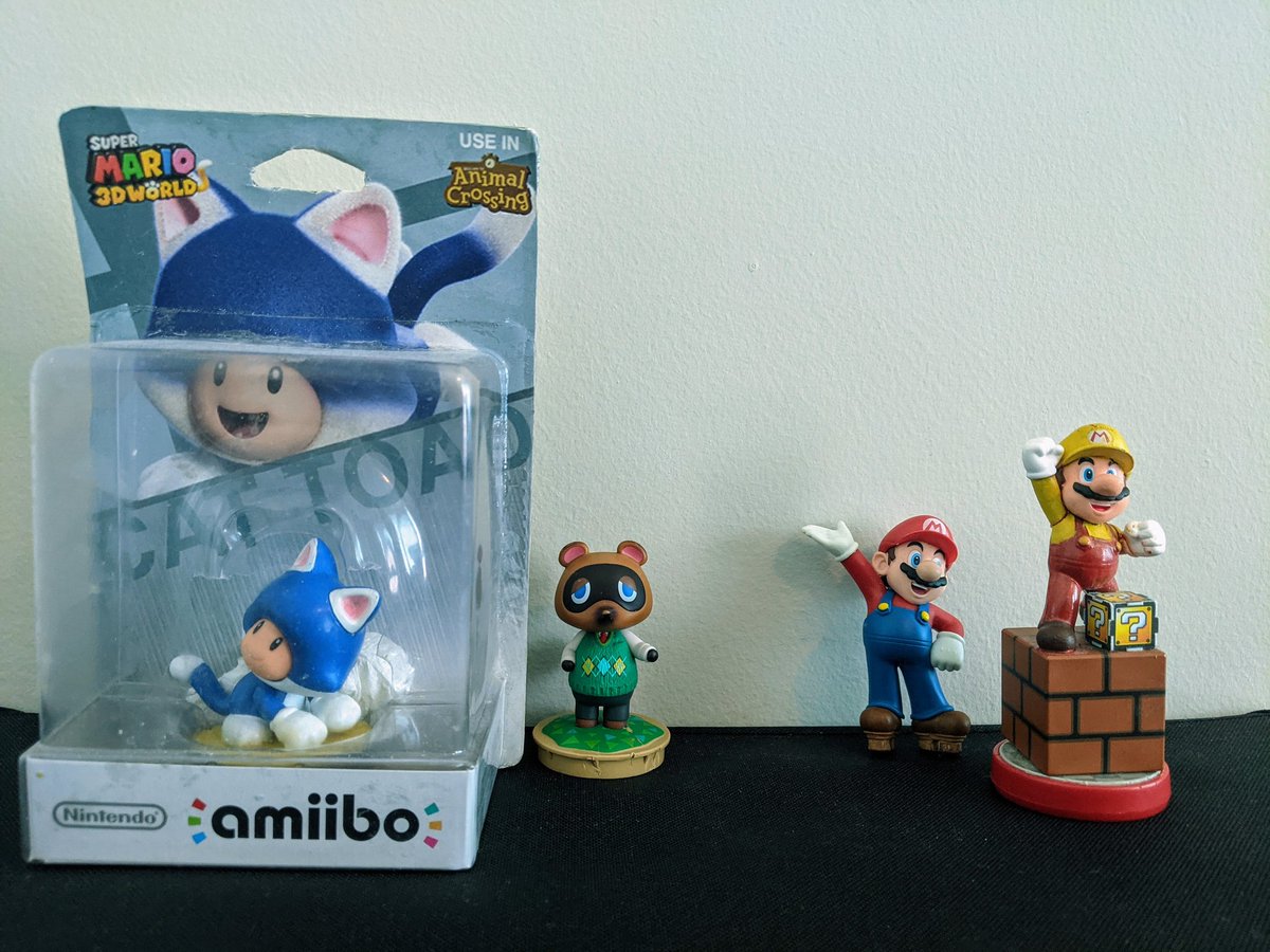 Left: a Cat Toad figurine on a yellow base, with box art using his artwork from Super Mario 3D World. A symbol on the top right of the box says "use in Animal Crossing". Next to it is a Tom Nook (Animal Crossing) amiibo removed from its base.

Right: a Mario (Mario Party) amiibo removed from its base, and next to it, a Mario Party amiibo base with a brown brick block on top, and on top of that, a miniature cardboard question mark (?) block, sitting next to Mario with a yellow hat and red overalls, meant to mimic his color palette from his Super Mario Maker outfit.