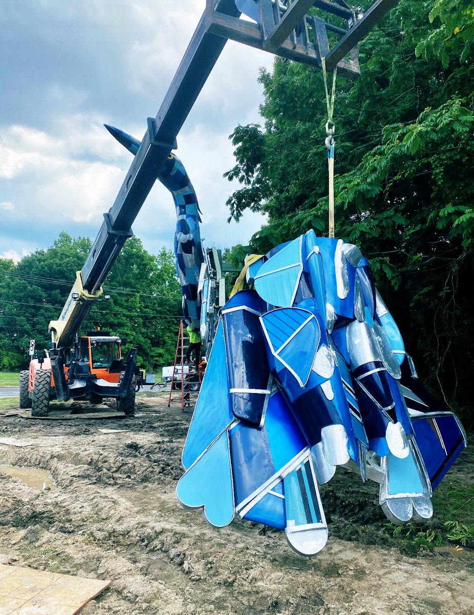 This is a picture of the construction site with a crane holding the wings of the blue Heron sculpture. The blue hair and head speaking out in the distance. It shows all of the mud installation team had to over come over the weekend.