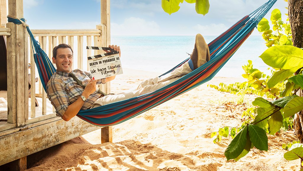 Ralf Little in a hammock holding a clapperboard