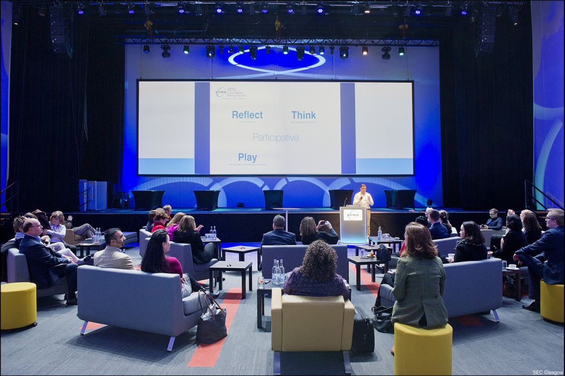 people in a meeting area facing a large screen