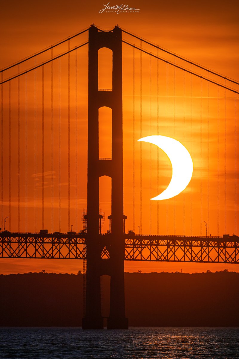 TrevorMahlmann's tweet photo. Holy moly, incredible view of the annular solar eclipse rising behind the mighty Mackinac Bridge in Michigan just now🤩🌙

⚙️/⬇️/🖼: https://t.co/fhT9frup54 https://t.co/sFkwGWUkPg