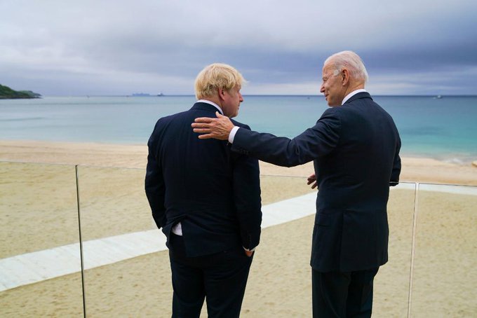 President Biden and Prime Minister Johnson talk while overlooking the water.