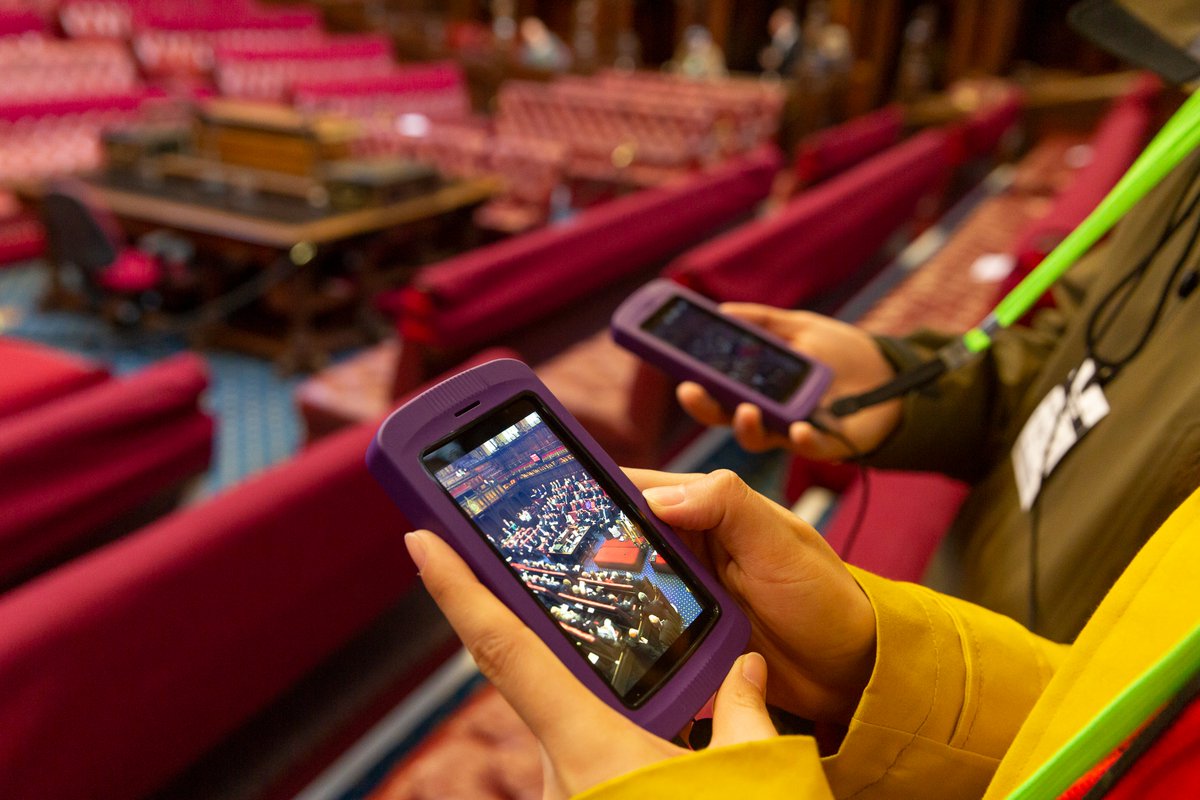 Two people's hands holding portable multimedia tour guide screens.