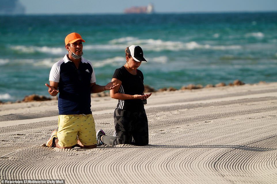 RMolinon's tweet photo. People pray on the beach outside the Champlain Towers South debris on Monday morning as the search for survivors continued. 

📷 Coverage by Reportajes El Molinon for @DailyMail https://t.co/t4vDLjNWHV