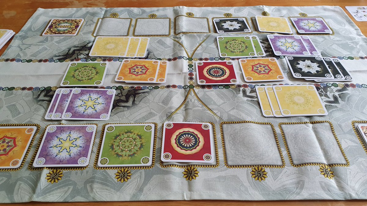 A game of Mandala in progress, with the colored square cards on the cloth board.