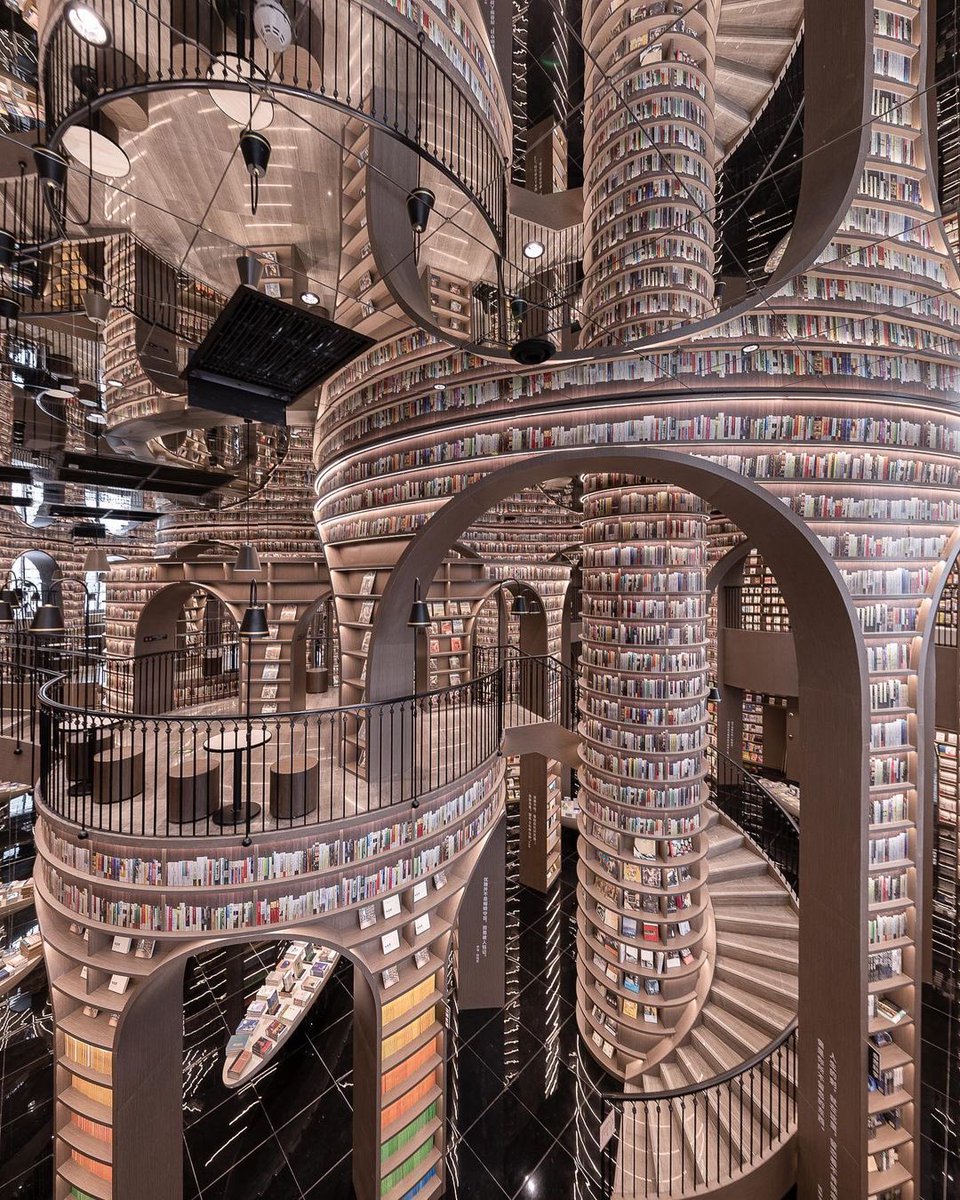 The interior of the Dujiangyan Zhongshuge bookstore by X+Living appears to go on forever with each of the internal arches reflected on the ceiling