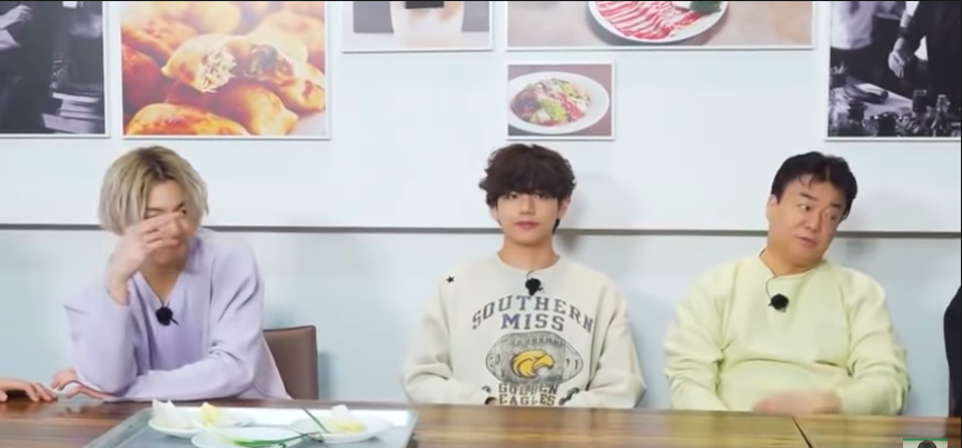 V from BTS sitting at a table in a Southern Miss sweatshirt