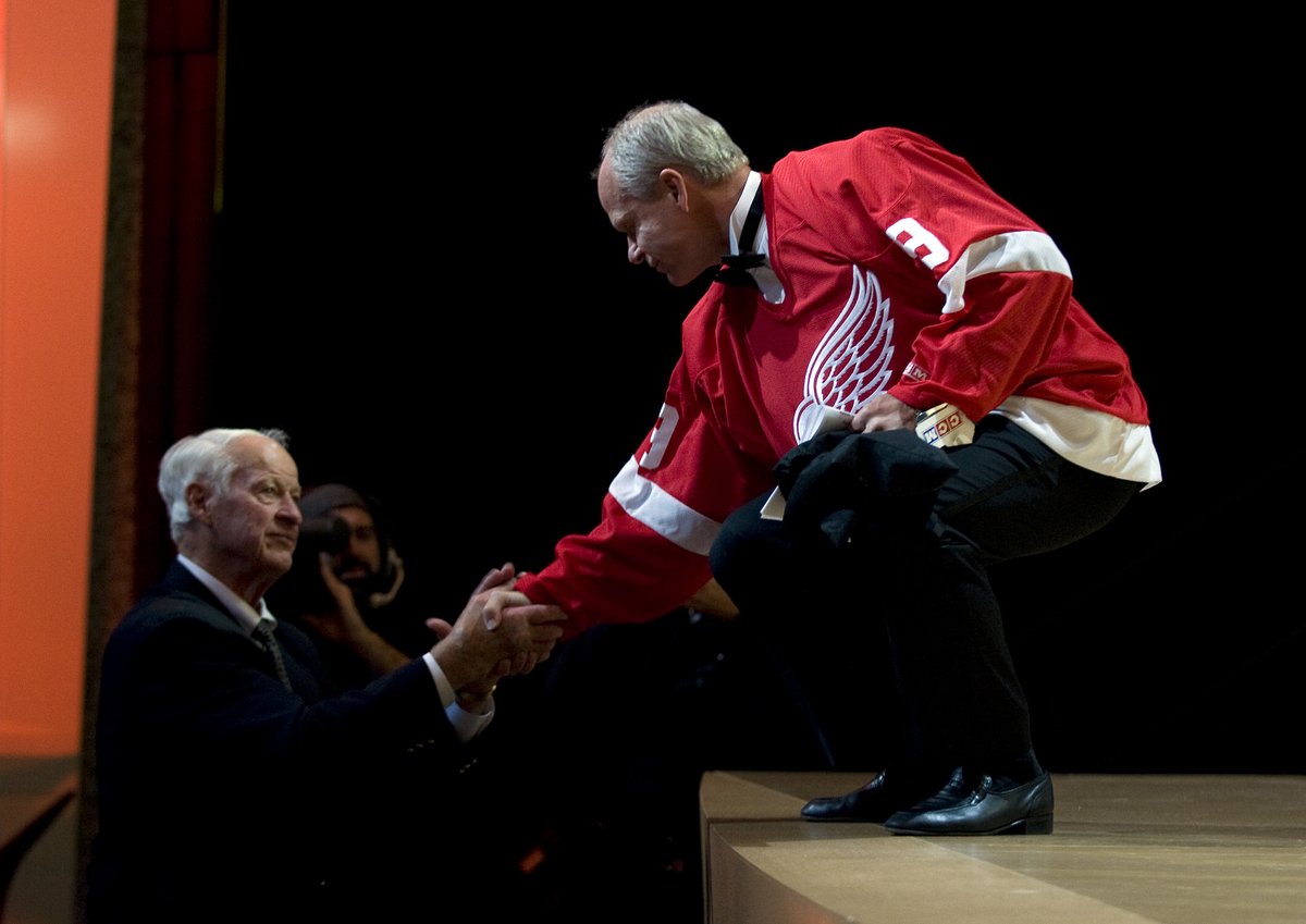 Mark Howe, wearing his father's Detroit Red Wings jersey, bends down at the edge of the stage to shake the hand of his father, Gordie Howe, during Mark's Hockey Hall of Fame Induction. Photo by Matthew Manor / HHOF-IIHF Images