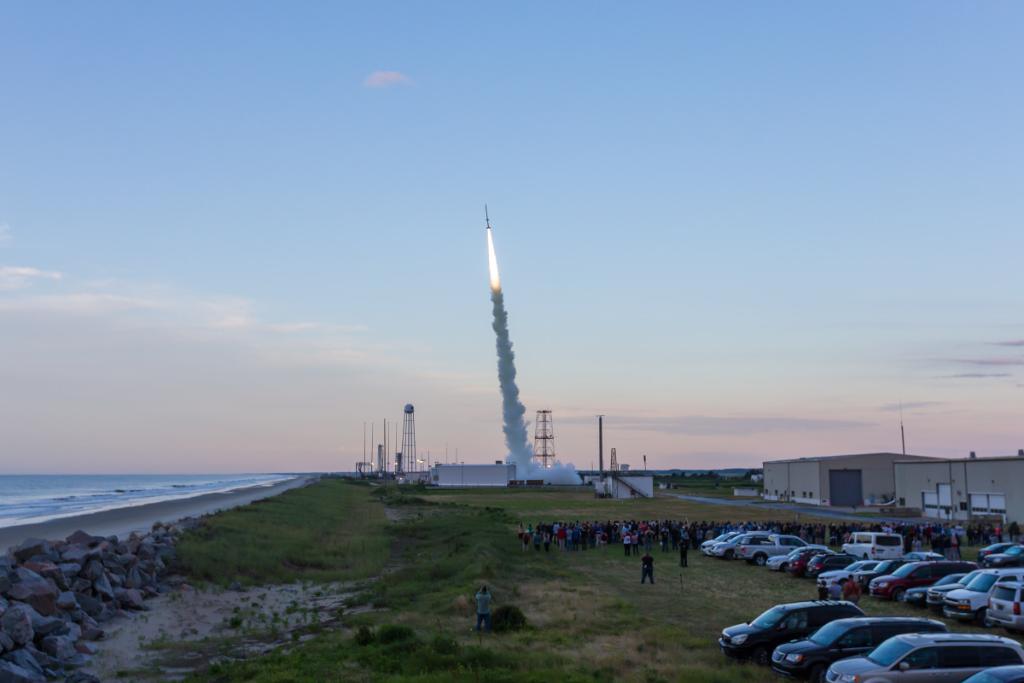 Sounding rocket launching at dawn with students lined up watching.