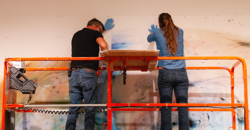 SDMA's tweet photo. This huge galaxy #drawing is one of 2! 💫
Here, our Assistant #Registrar closely examines the condition of each paper panel before handing them off to our Chief #Preparator and #MuseumTechnician for #installation—using magnets and a carefully laid out grid on our #gallery wall.