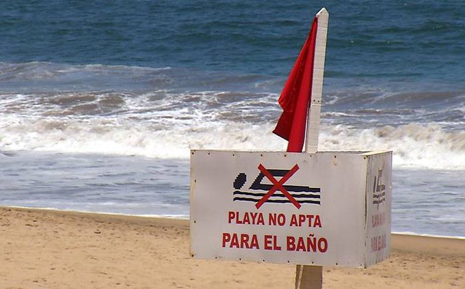 Bandera roja instalada en la arena de una playa.