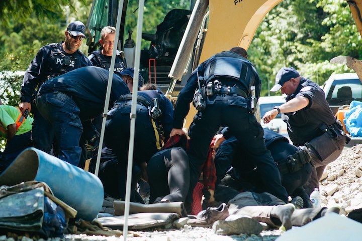 RCMP raided #FairyCreek’s Eden Camp at 1:30 AM yesterday, and again at 9:30 AM. 6 arrests yesterday at Eden. 

Image: 6 officers tackle a young woman. Extractions were made with a jackhammer, excavator and other pieces of heavy equipment used next to the arrestees.

📷: <a href="/oracogan/">Ora Cogan</a>