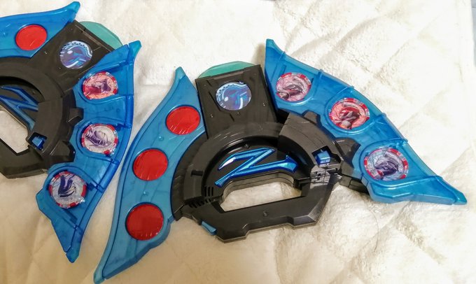 ウルトラゼットライザーメモリアル。見た目の主な違いはブレードの形状と色。スピーカー穴が増え、音質も向上。カード挿入やブレード可動もおそらく改善が見られる。劇中モードにすれば、付属のメダルでジードやカブラギの変身が代用でき、DX版のメダルも認識する為、完全にDX版の上位互換。 