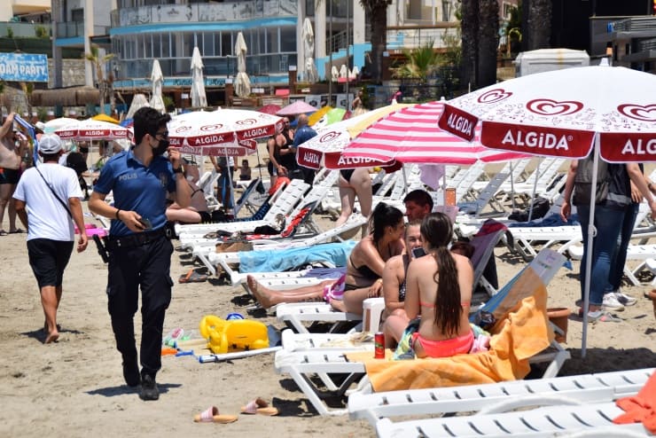 Kuşadası'nda bugün: Yasaktan muaf yabancı turistler, sıcak havada denize girerek serinlerken Türk vatandaşı olduğu tespit edilenlere ceza kesildi.