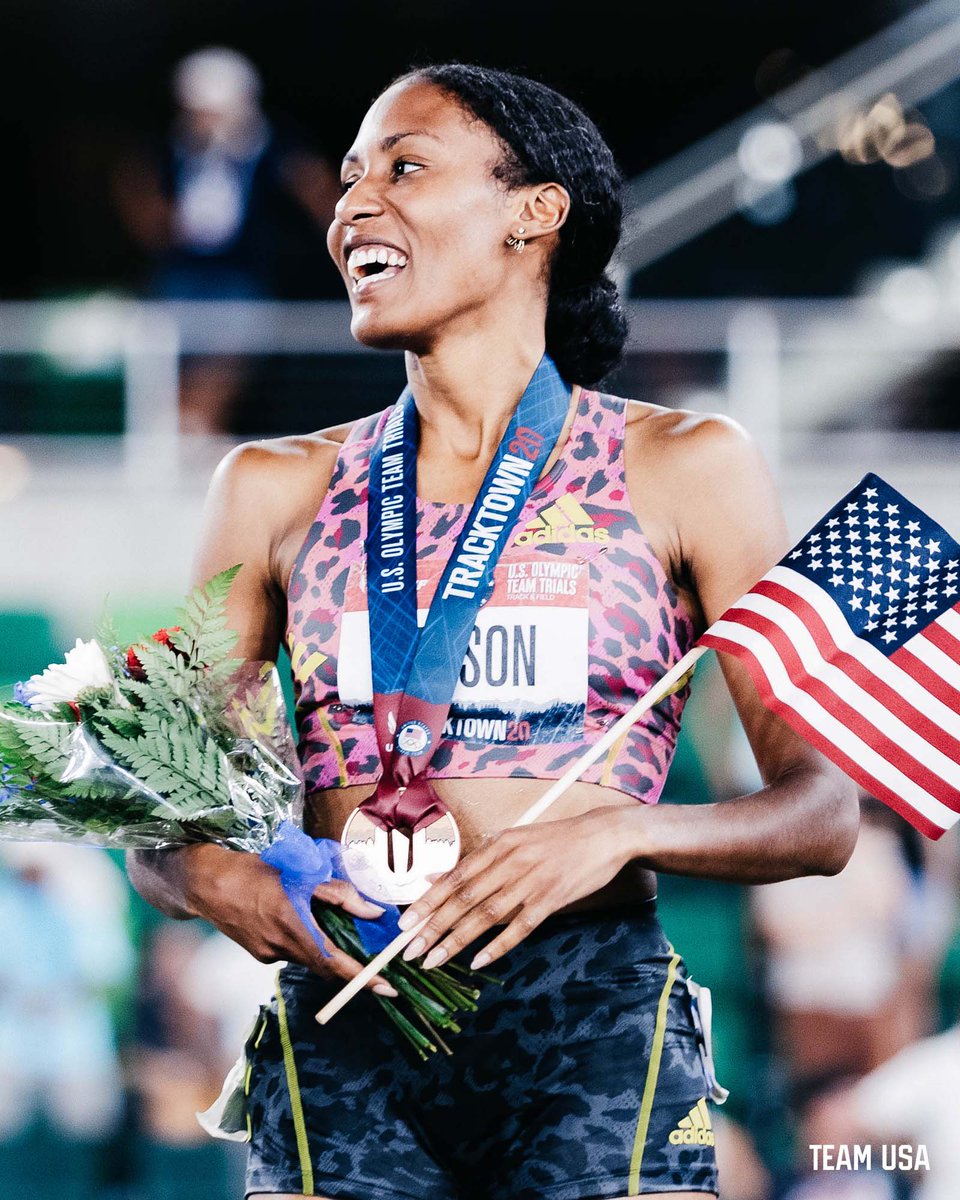 athletes smiling and holding a bouquet and flag