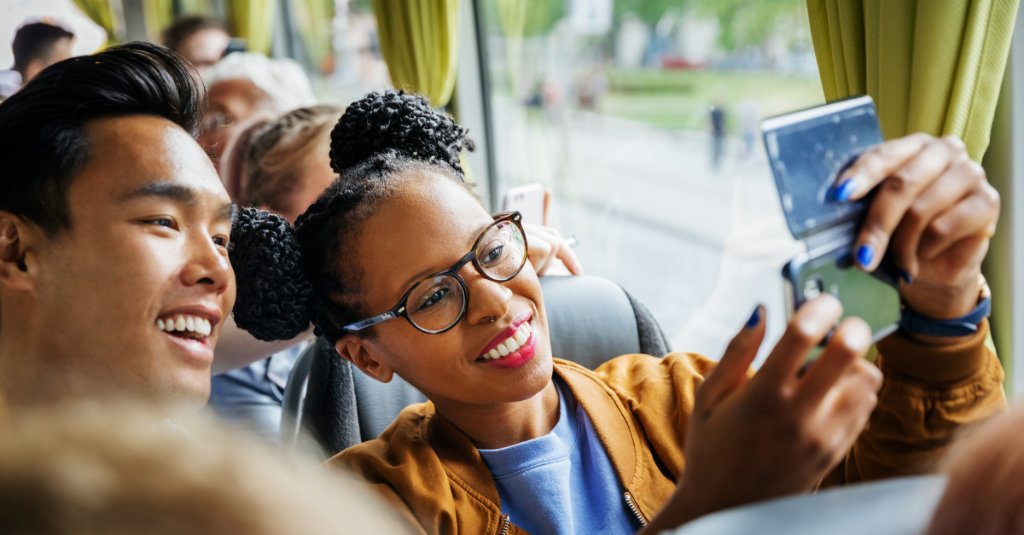 Girl and boy on bus laughing and taking selfie together on their phone