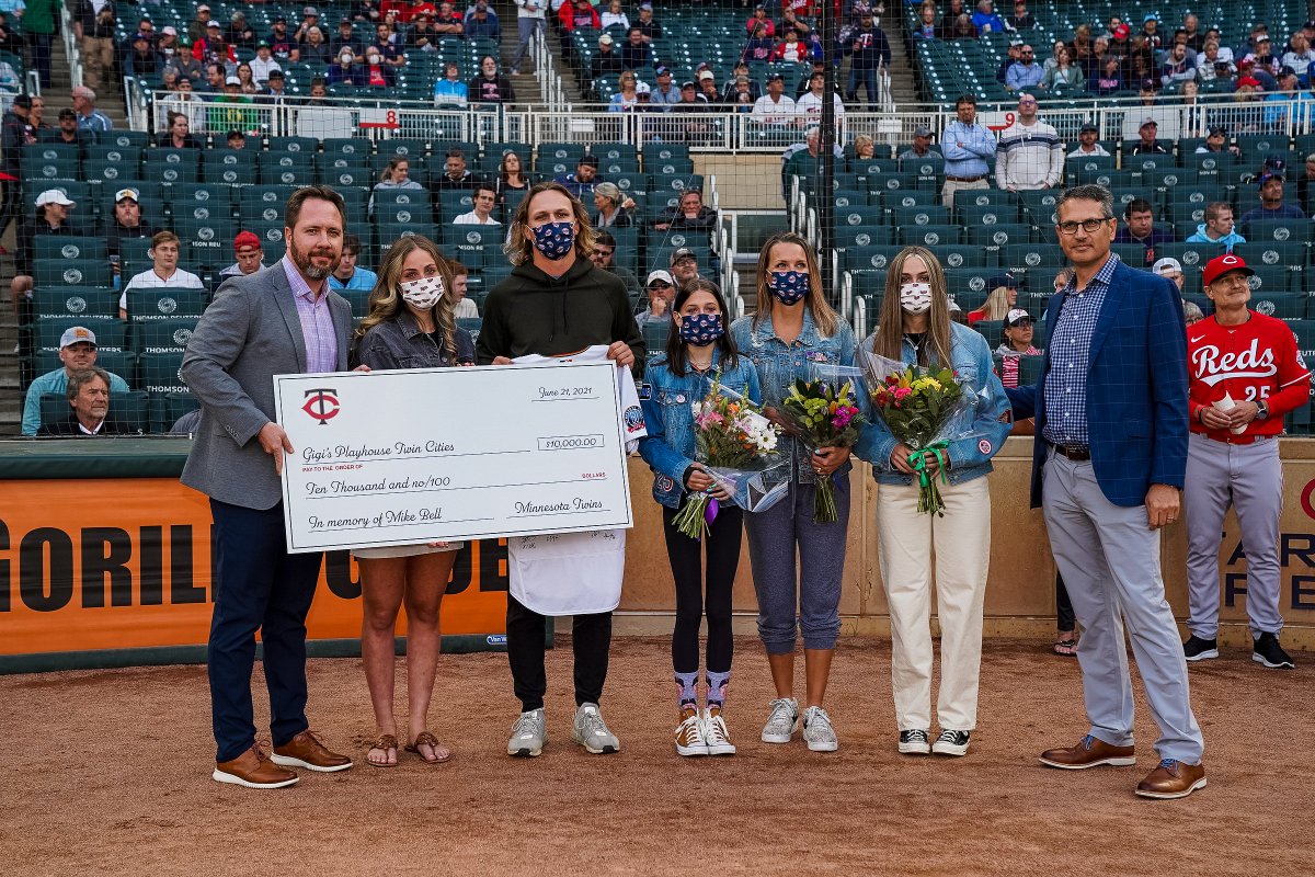 Twins's tweet photo. We honor our late bench coach Mike Bell as we take on the Reds, managed by his brother David. The Bell family was presented with Mike's 2020 jersey signed by the team and a donation to Gigi’s Playhouse. Mike's wife Kelly threw out the first pitch. Tonight we play for Mike! ❤💙 https://t.co/GtlAy42dDU