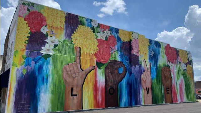 iyellowgroup's tweet photo. "The "Love for All" mural was painted on the side of a two-story building at the intersection of Third Street and First Avenue in Faribault...The mural can be appreciated in English, American Sign Language (ASL) and Braille. On top of that, there will be an option for people... https://t.co/MvNteMyqiP