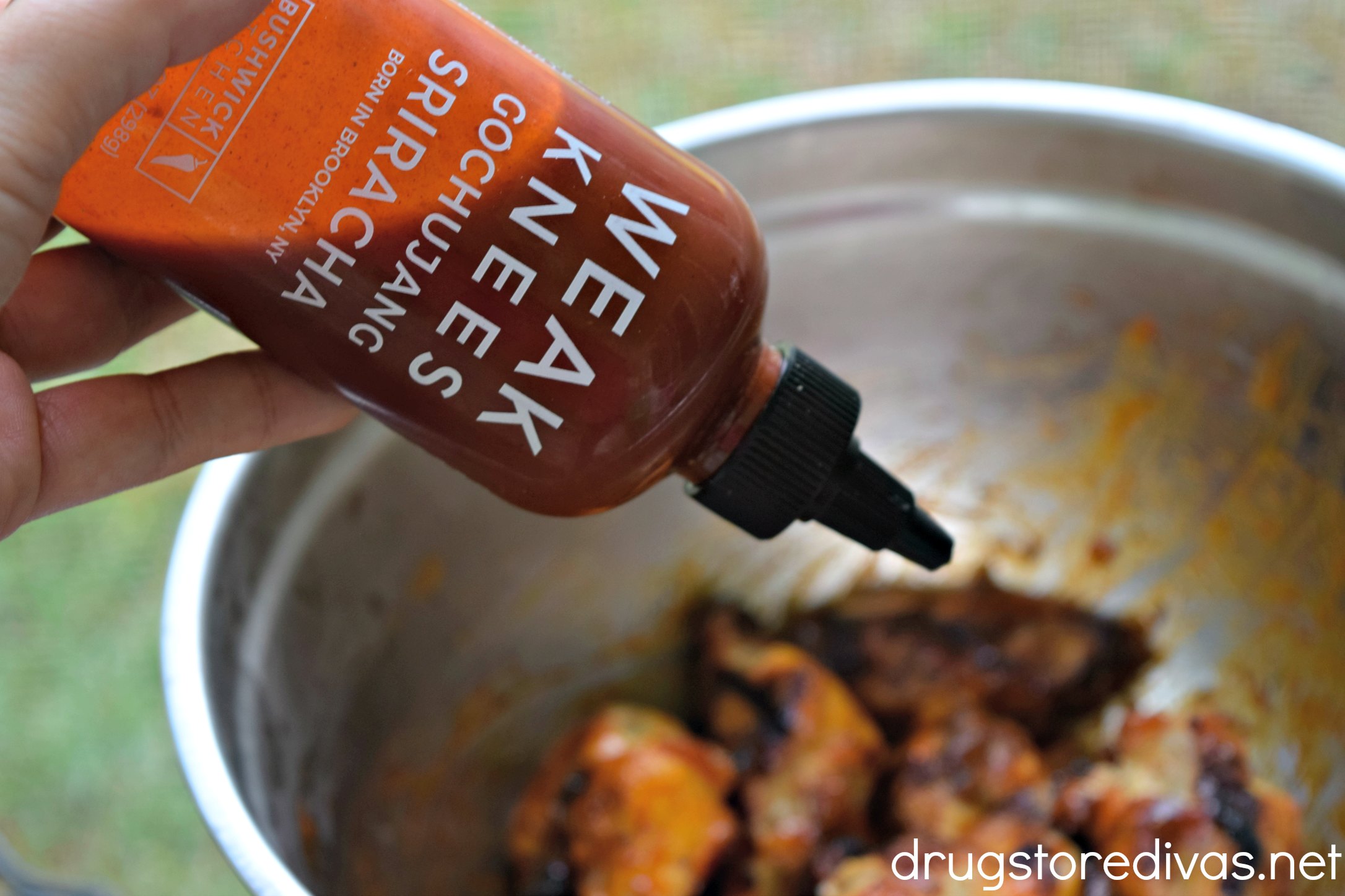 A bottle of hot sauce being poured on wings.