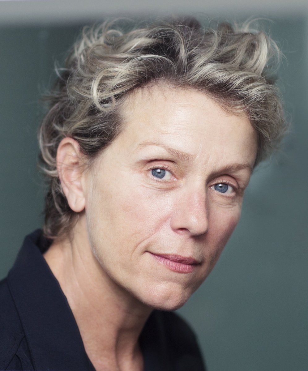 Frances McDormand looks at the camera while smiling slightly.