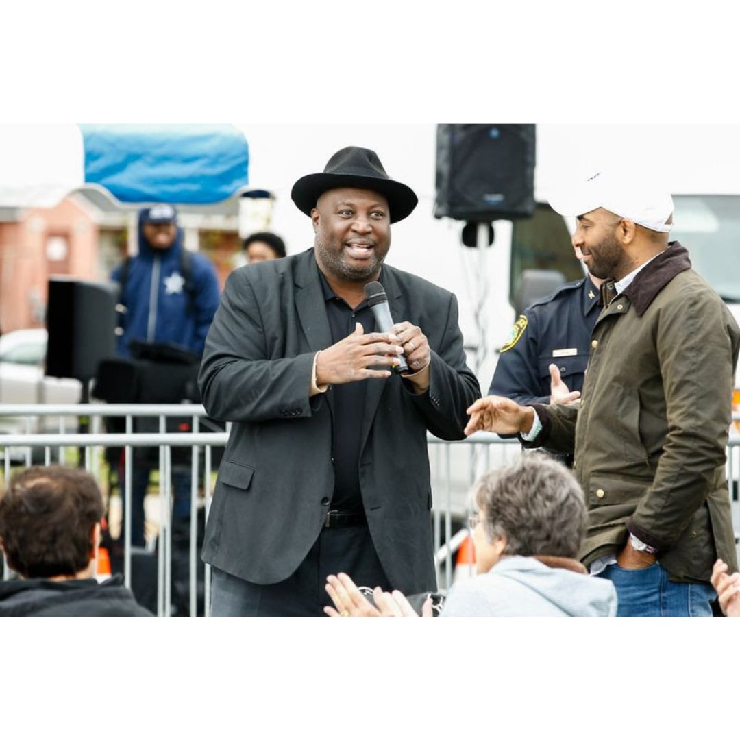 Male community leader holding a microphone addressing a crowd of people