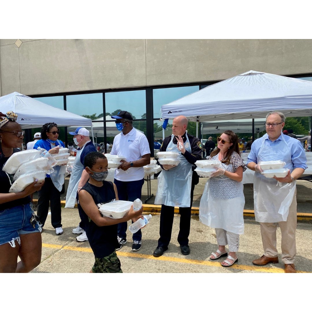 Line of volunteers holding to-go food boxes for community members passing by