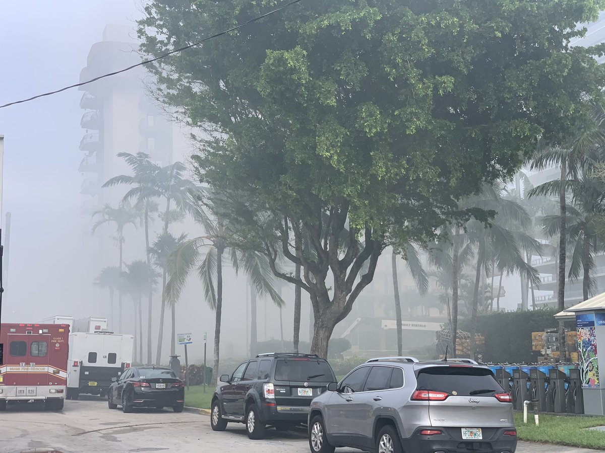 A small memorial to the missing has gone up near the Champlain Towers South condo complex collapse in Surfside, Fla., as smoke billows from the building