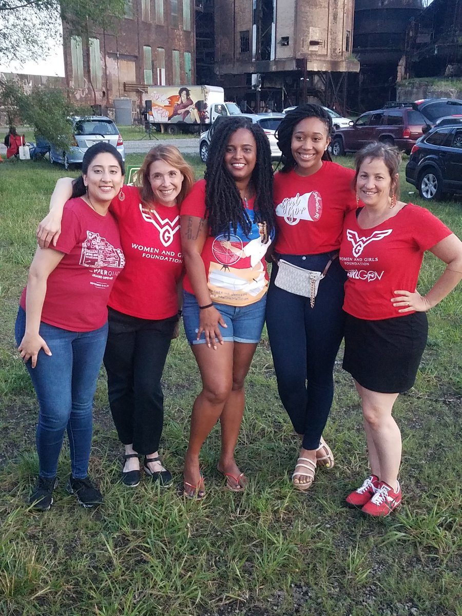Members of The Women and Girls Foundation Staff standing in front of the cars parked for the 
drive-in carpool cinema.