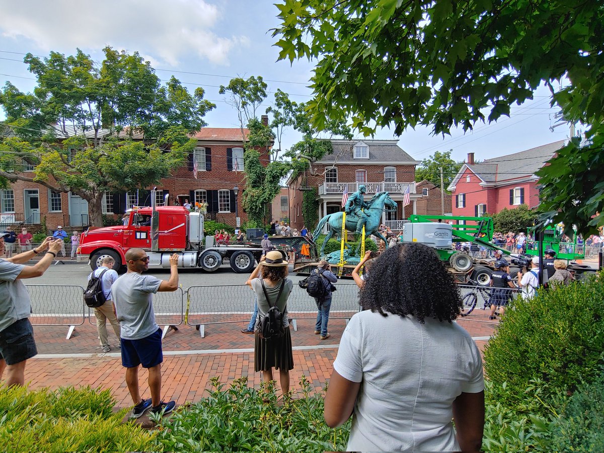 Jalane_Schmidt's tweet photo. Stonewall Jackson gets hauled out of Charlottesville, ass first, with U.S. flags waving behind him. The crowd yells "THANK YOU!!" to the workers on the contracting team as they drive their trucks away. #CvilleStatuesDown https://t.co/7D40x6Opif