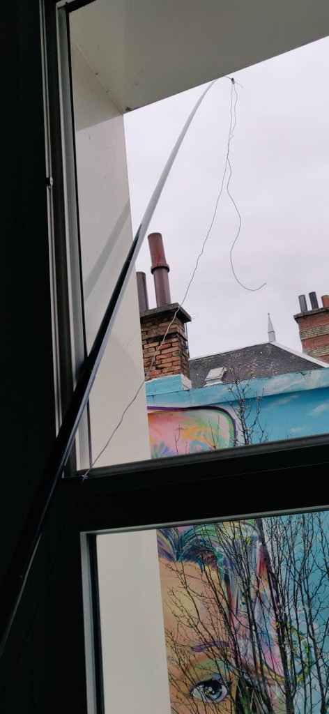 Canne à pêche qui sort de la fenêtre. Le fil de l'antenne est scotché dessus et pend ensuite vers le sol