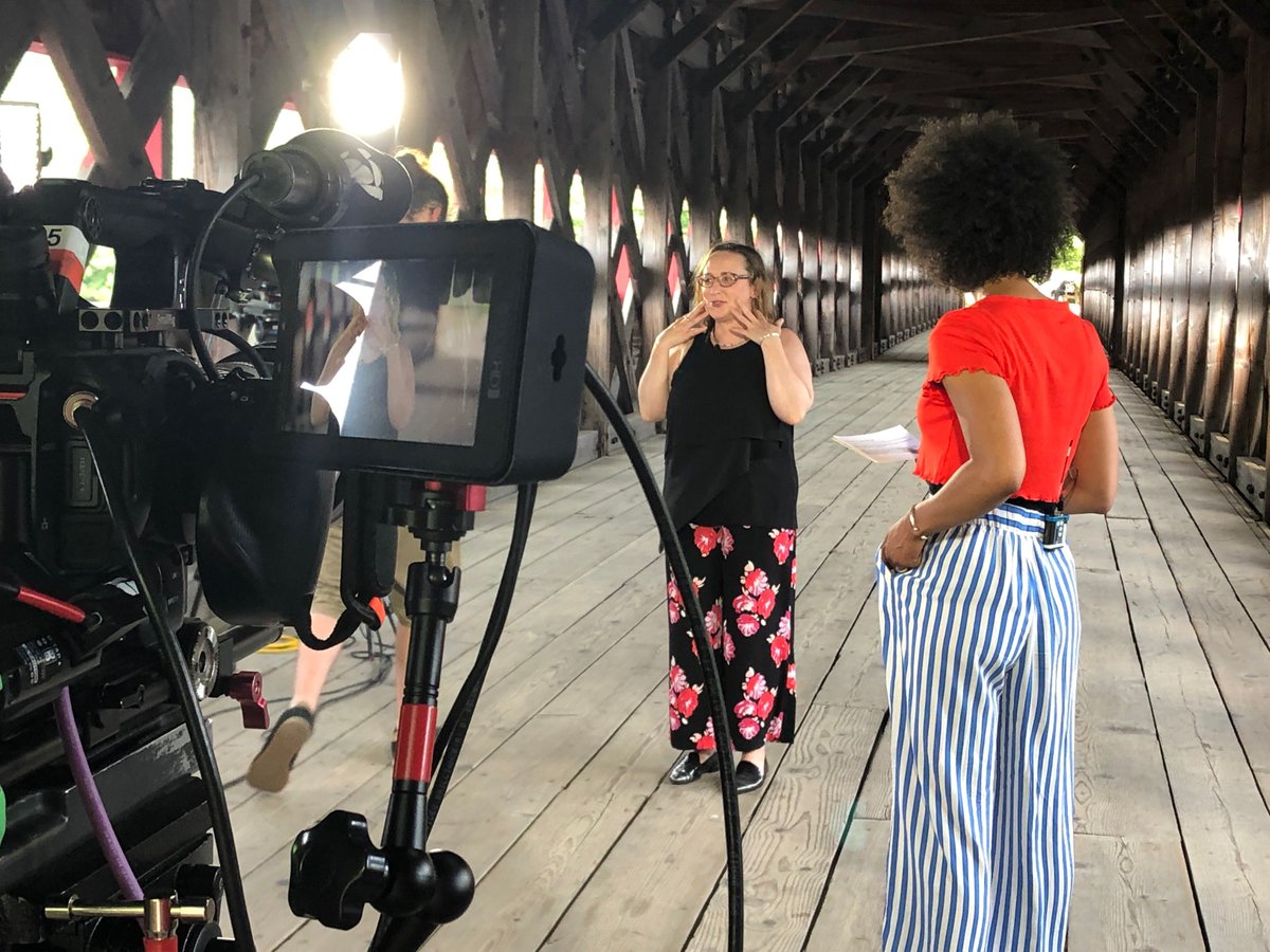Une équipe de tournage en entrevue avec une femme sur un pont couvert.