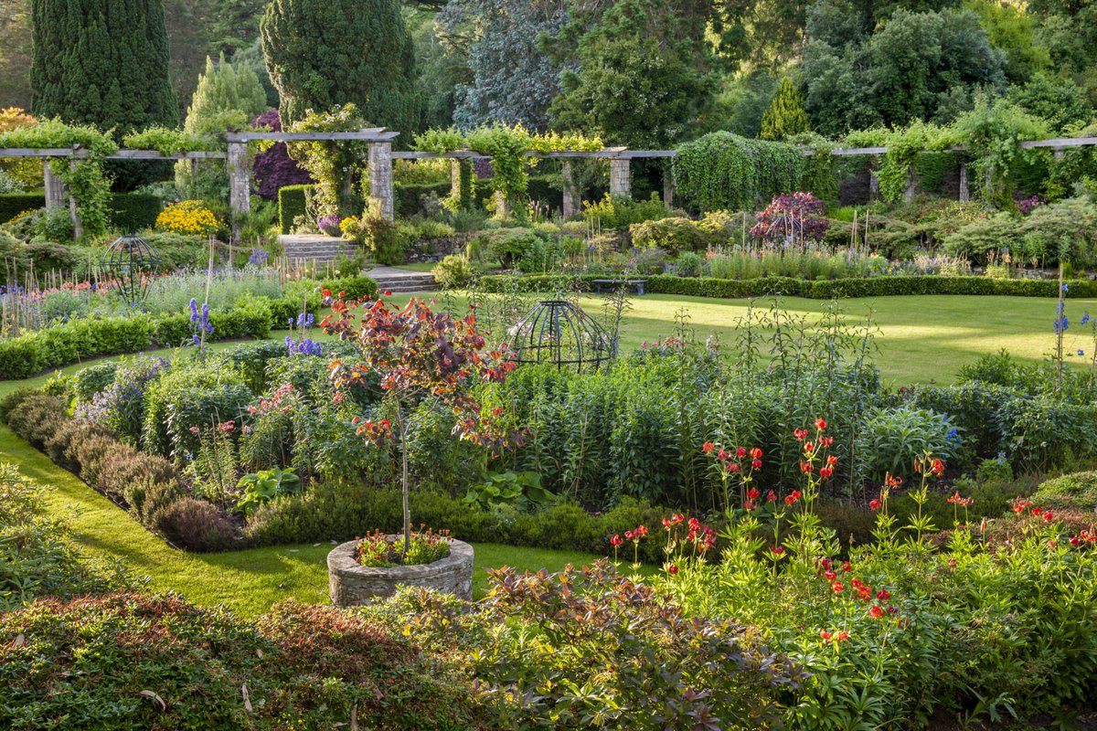 The Sunk Garden at Mount Stewart in summer, a round garden with flower beds around the outside and a neat lawn at the centre.
