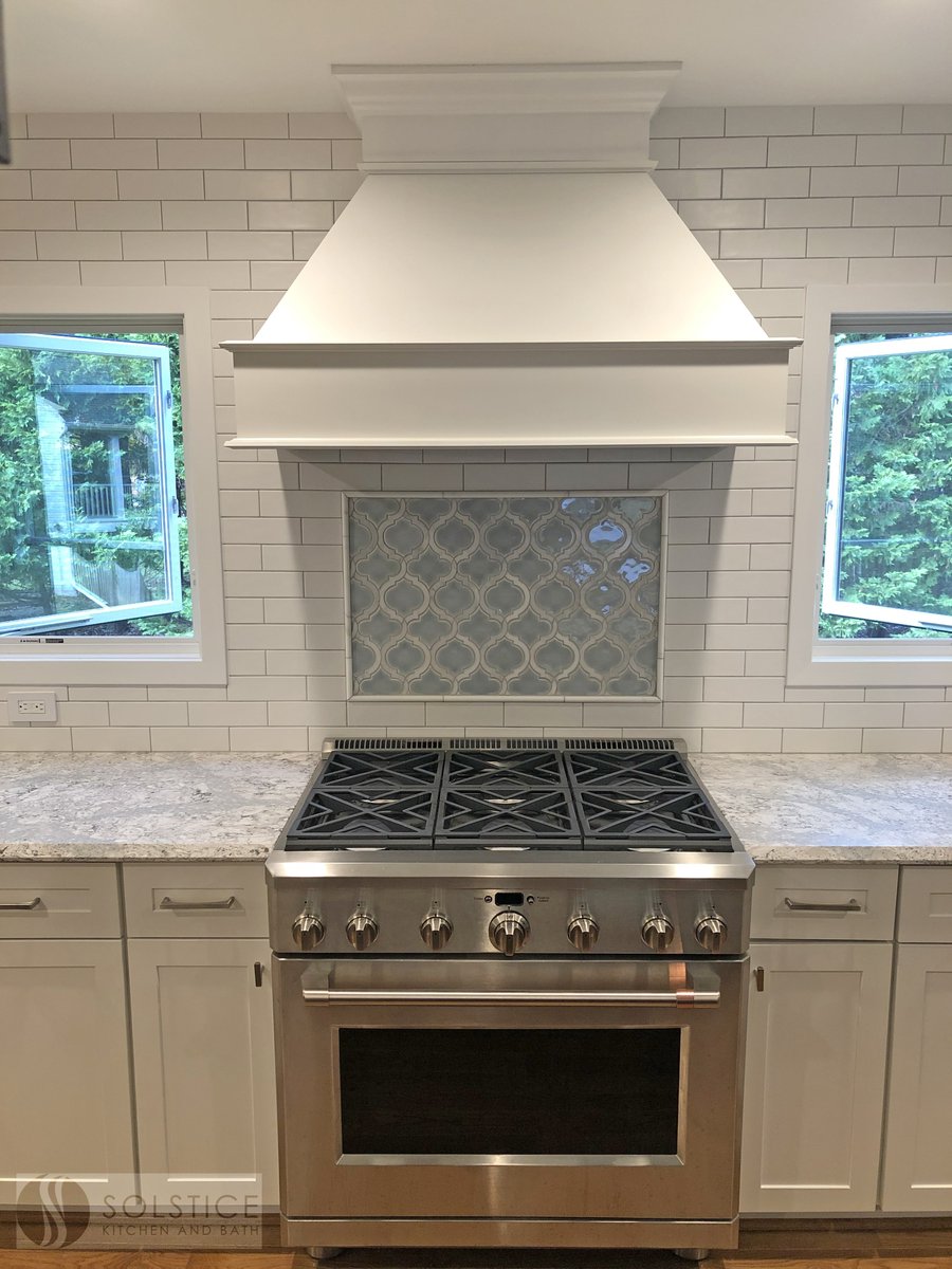 This custom hood is set against a backdrop of classic white subway tile and accented by a blue arabesque tile feature to create a stunning focal point in this #MillersvilleMD #kitchendesign. Work with our design team to find the ideal layout, materials, and colors for your home!