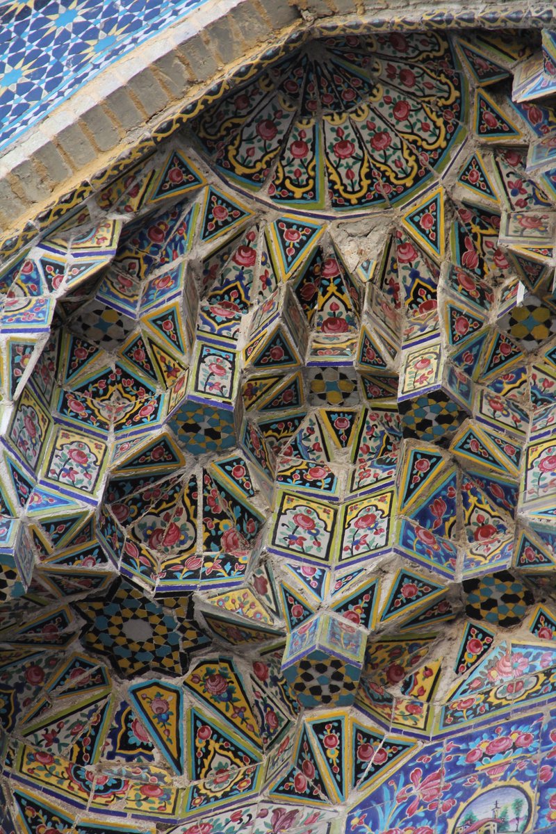 Brightly painted geometric tiles adorn the entry portal of a small shop is Shiraz.