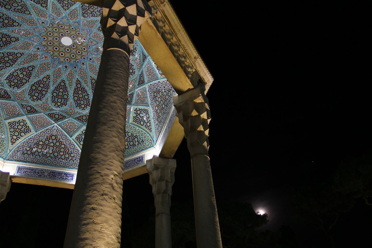 A view at night looking up into the dome where the poet Hafez is buried. It's all tiles, in a variety of blues, golds, greens, and other colors in striking geometric patterns.