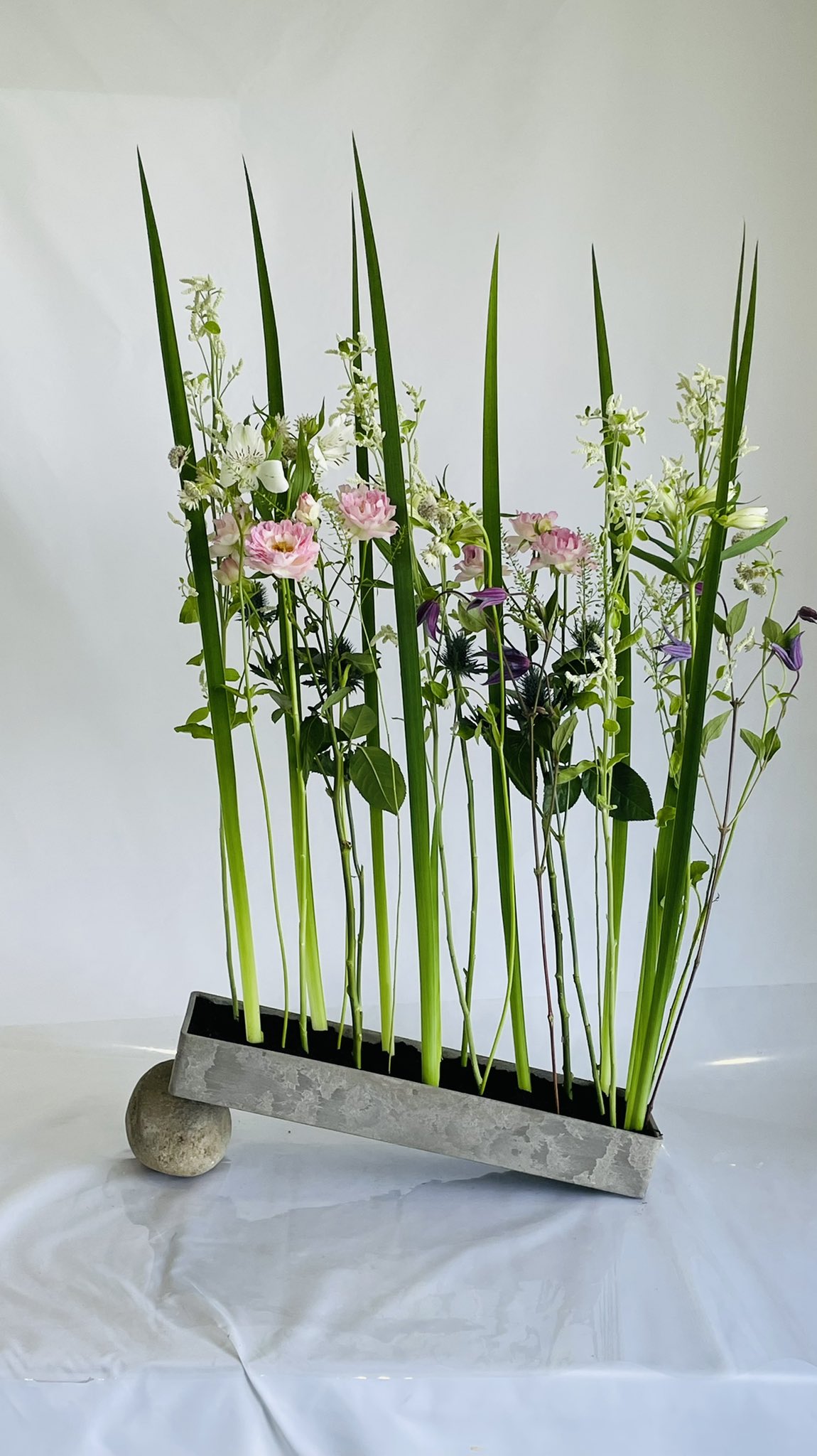 花まつフラワーアカデミー フラワーアレンジメント 薔薇 品種名 シーアネモネ を使って テッセン アルストロメリア オクラレルカ エレンジュウム シルバーキャット タラスピ マヨール 器の下には 石 M I 花まつフラワーアカデミー 花の