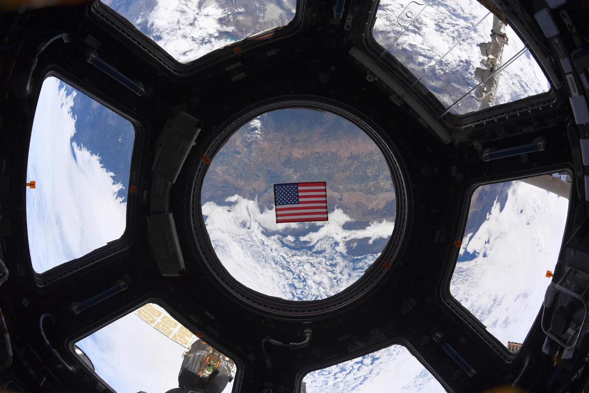 A United States flag floats in the cupola as @Space_Station flies above California.
