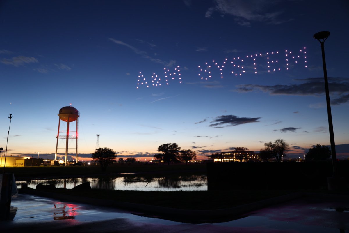 Sunset over RELLIS Campus with 4th of July drones lighting up the sky spelling out A & M System. 