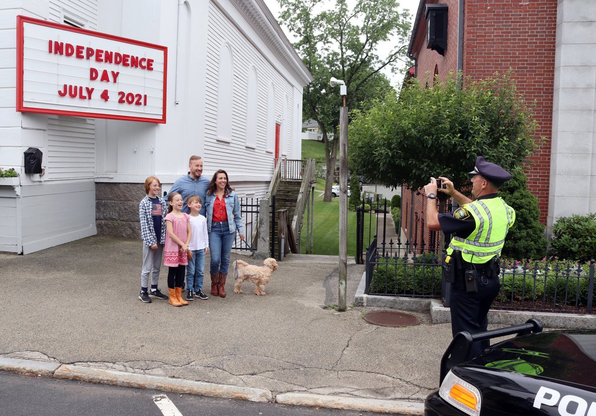 Community. Special Officer Michael Murray takes a pic for a family after the Fourth of July Parade outside the historic Loring Hall in Downtown Hingham.
