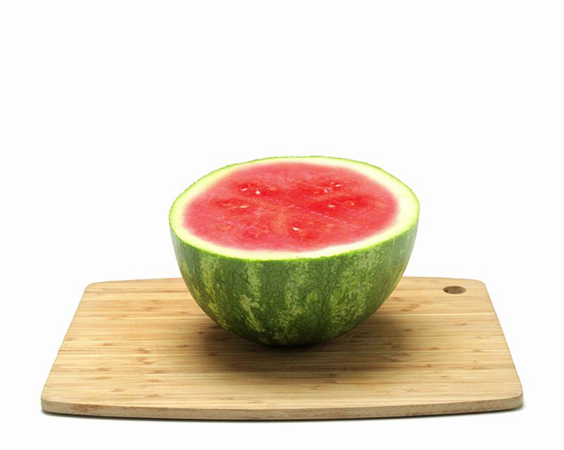 A watermelon cut in half on a wooden board
