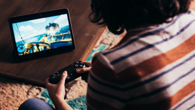 Lifestyle imagery of a person playing Sea of Thieves on an iPad with a Playstation controller using Cloud Gaming with Xbox Game Pass Ultimate. 