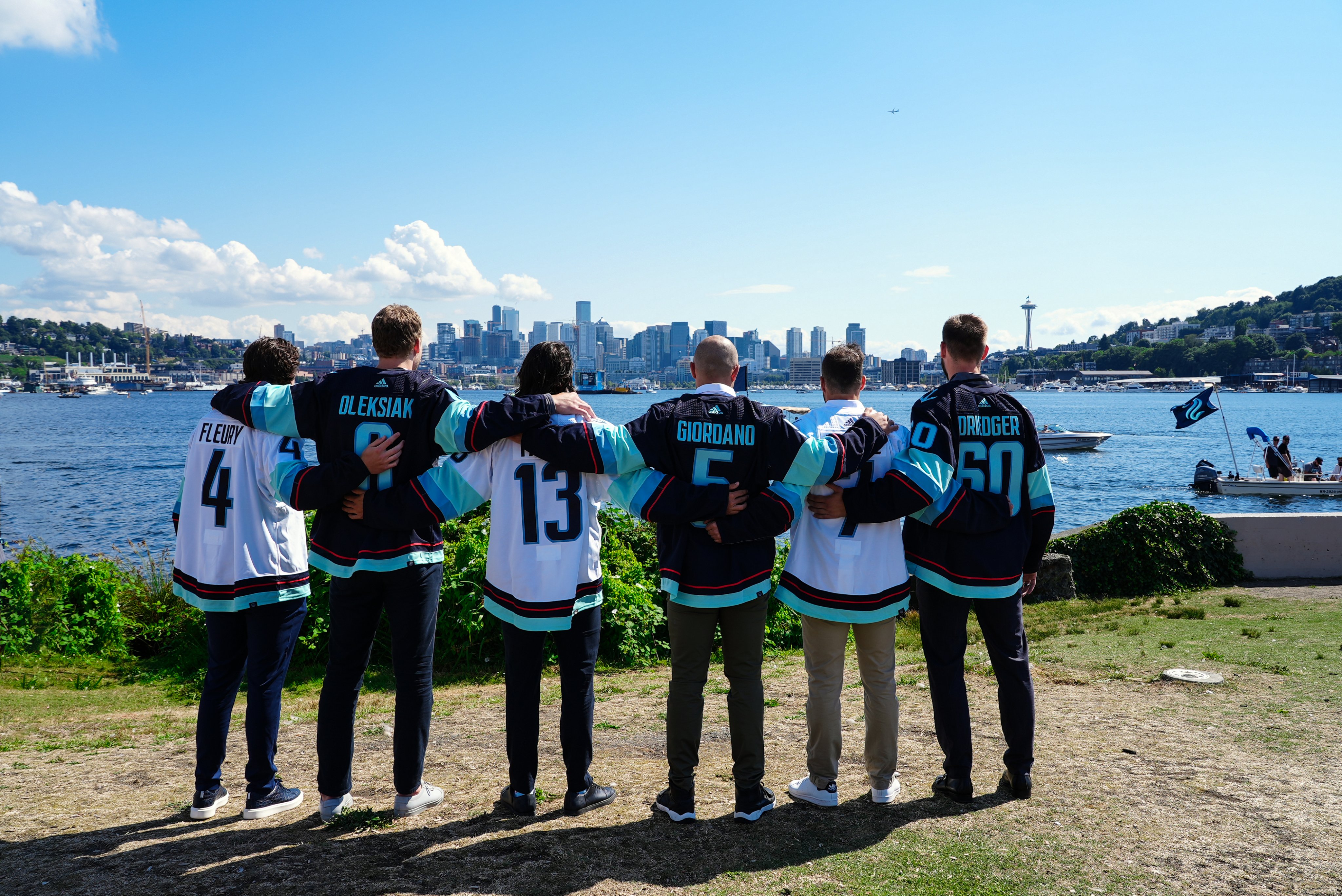 (left to right) Haydn Fluery, Jamie Oleksiak, Brandon Tanev, Mark Giordarno, Jordan Elebre and Chris Driedger posing in the new kraken jerseys at Gas Works park post-Expansion draft - facing away from camera