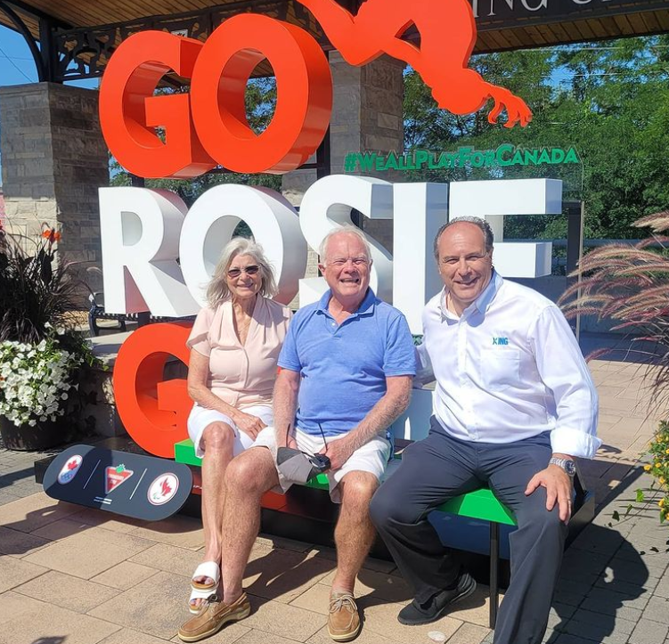 KingTownship's tweet photo. You may notice something new at King and Keele -- the Go Rosie Go sign showing our support for King City trampoline gymnast Rosie MacLennan. She's attempting to win her third gold medal in Tokyo. Mayor Steve Pellegrini, right, at the sign with Rosie's parents. #gorosiego https://t.co/1cb2FVGQTH