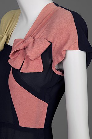 kateStrasdin's tweet image. #Colourblocking is an effective decoration in #1940s tricot knit design. Mostly dark navy, the brighter decorations have been pieced in a mustard and coral bow, contrasting on each side of the body, emphasising the then fashionably square shoulders @GoldsteinMuseum #dresshistory