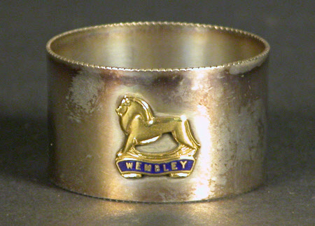 A metal napkin ring bearing a lion crest with Wembley beneath.