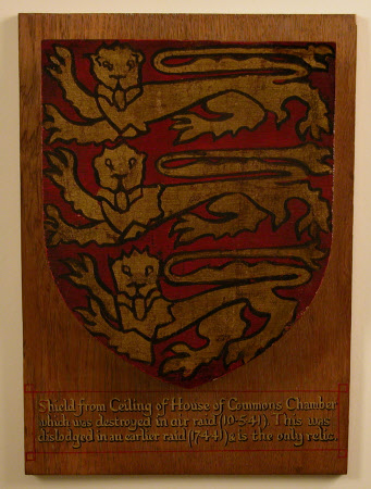 A shield from the ceiling of the Chamber of the old House of Commons. Painted with three lions couchant in gilt and mounted on an oak board. Marked "Shield from Ceiling of House of Commons Chamber which was destroyed in air raid (10-5-41). This was dislodged in an earlier raid (17-4-41) & is the only relic."