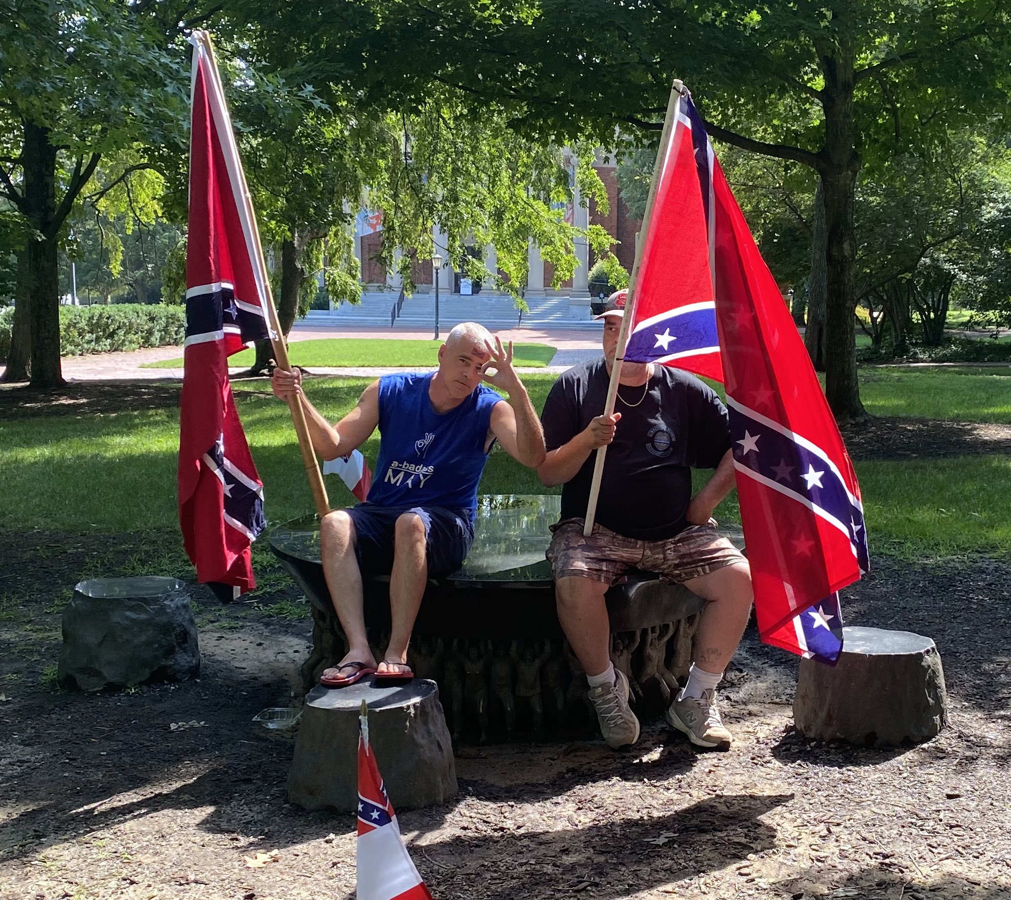 Neo-Confederates Thomas May and Joey Wardwell sit on top of the Unsung Founders Memorial, a monument honoring the enslaved and free Black people who built the University of North Carolina. May flashes a “white power” hand signal. Chapel Hill, NC, July 10, 2021.