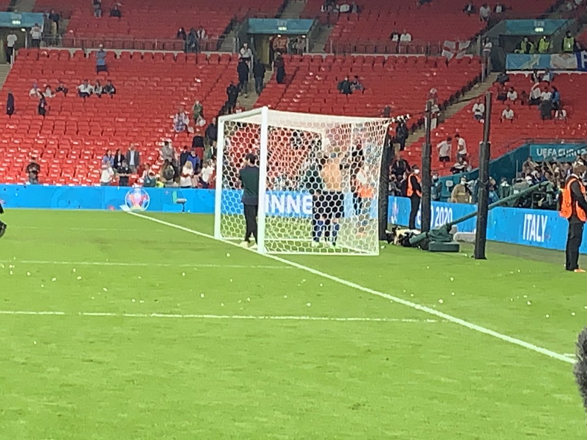 The Italians are cutting pieces of the goal netting to bring home