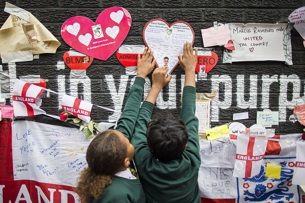 Young children post messages of support on the wall in Withington, Manchester bearing the face of England striker Marcus Rashford after the mural was defaced following his penalty miss in the Final of #euro2020 | 📷 for @welloffside